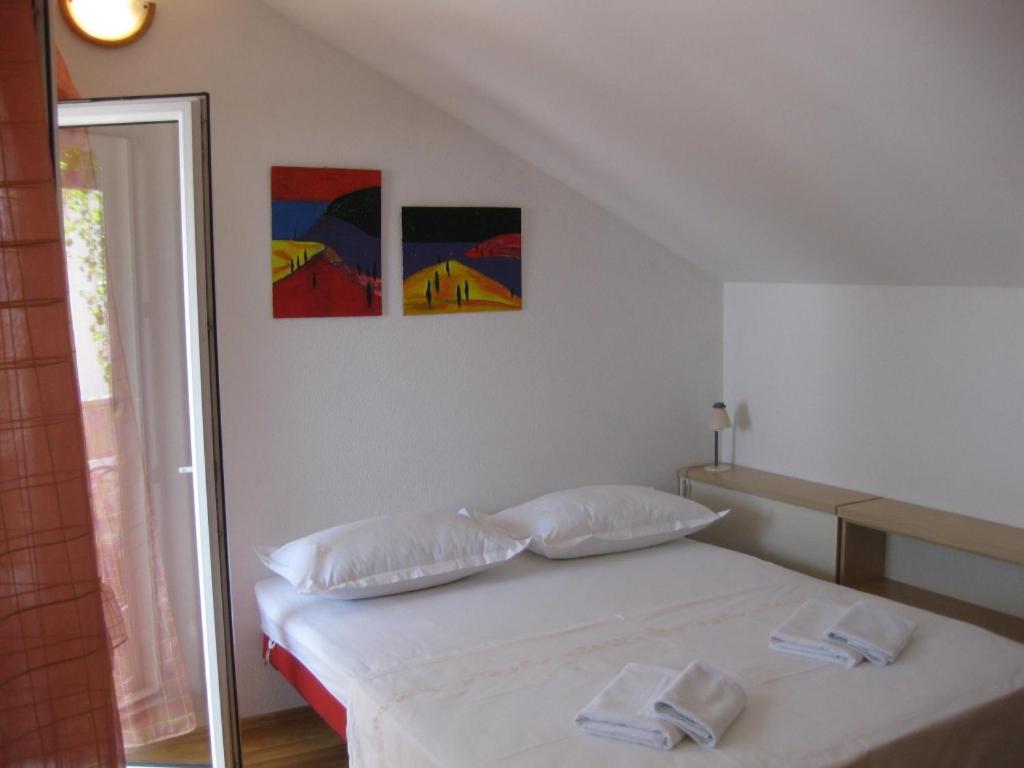uma cama branca num quarto com duas pinturas na parede em Apartment in Bol with sea view, terrace, air conditioning, WiFi 3739-1 em Bol