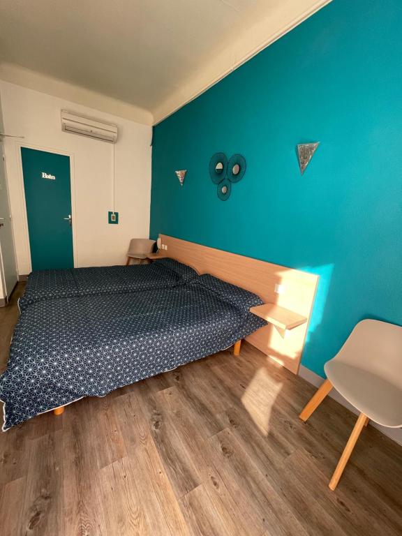 a bedroom with a bed and a blue wall at Hôtel Colisée-Verdun Centre Gare Saint-Roch in Montpellier