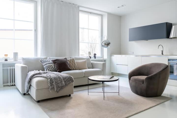 Sala de estar blanca con sofá y silla en Spacious and central apartment with private sauna, en Helsinki