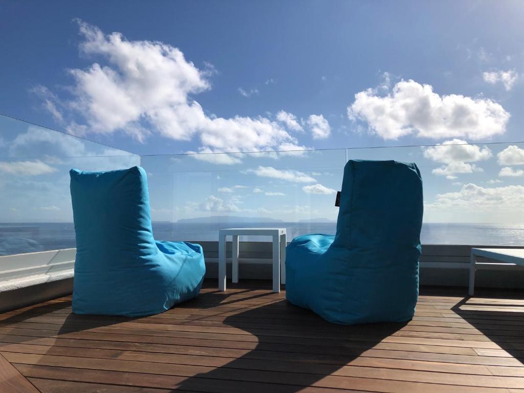 two blue chairs sitting on a deck looking out at the ocean at Luxurious Penthouse Suite direct at sea in Caniço