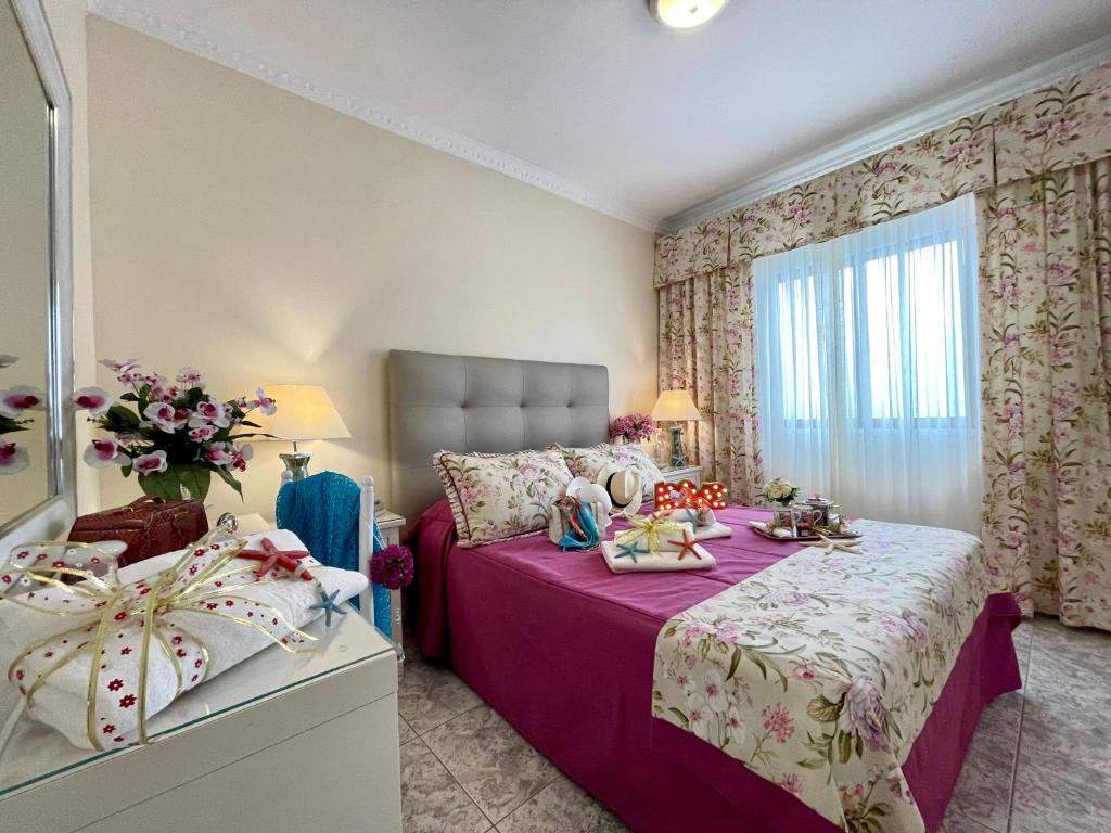 a bedroom with a bed with purple sheets and a window at EmyCanarias Primera Línea De Playa in Arinaga