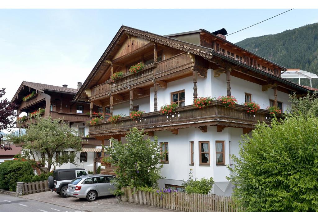 a white house with wooden balconies and cars parked outside at Haus Gaisberger in Mayrhofen