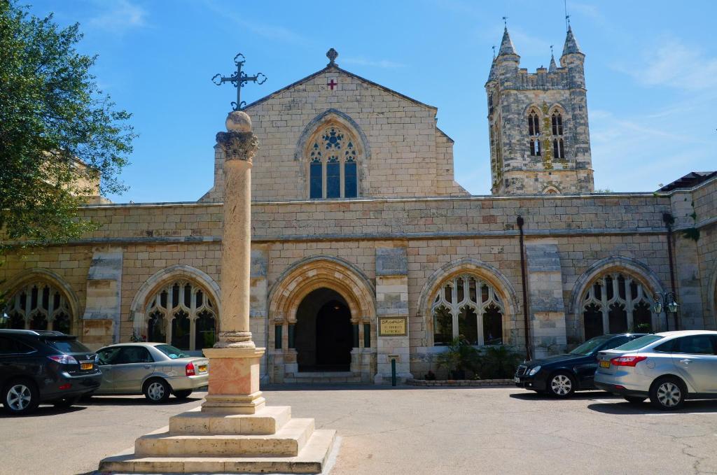 a church with cars parked in front of it at St. George’s Cathedral Pilgrim Guesthouse – Jerusalem in Jerusalem