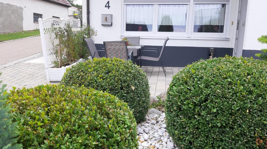 a patio with bushes and a table and chairs at 2 Zimmer Appartements in Heroldsatt in Heroldstatt