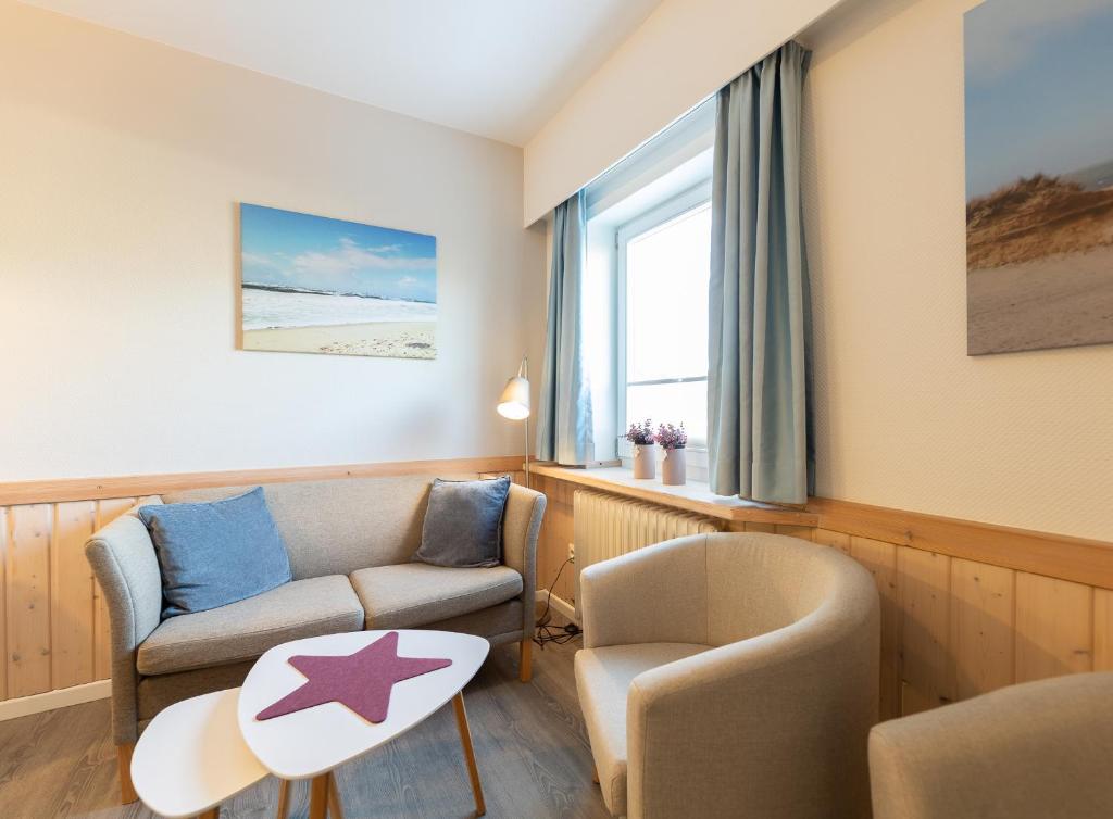 een woonkamer met een bank, een stoel en een tafel bij Appartement Beka 15 in Westerland