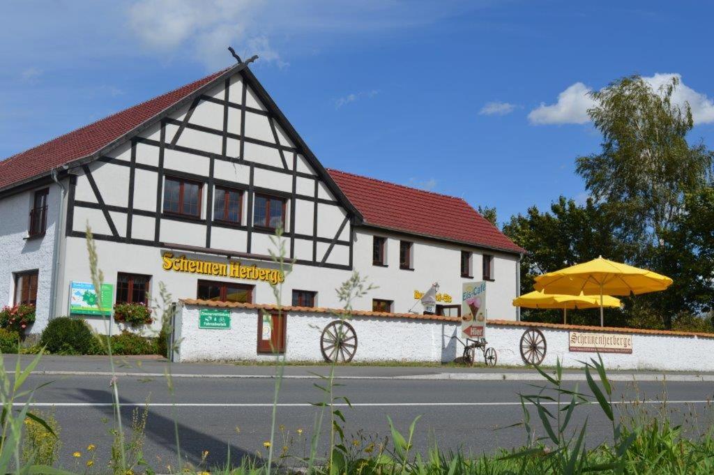 a white and black building with an umbrella at Scheunenherberge in Unterspreewald