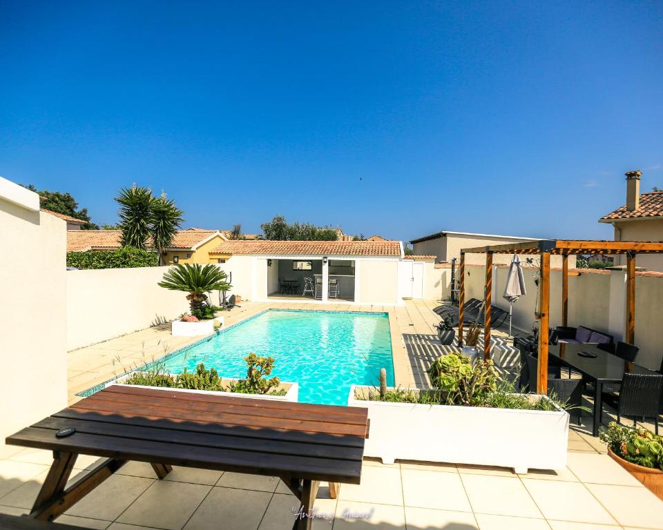 una piscina en un patio trasero con una mesa de madera en Résidence MARI, en Folelli