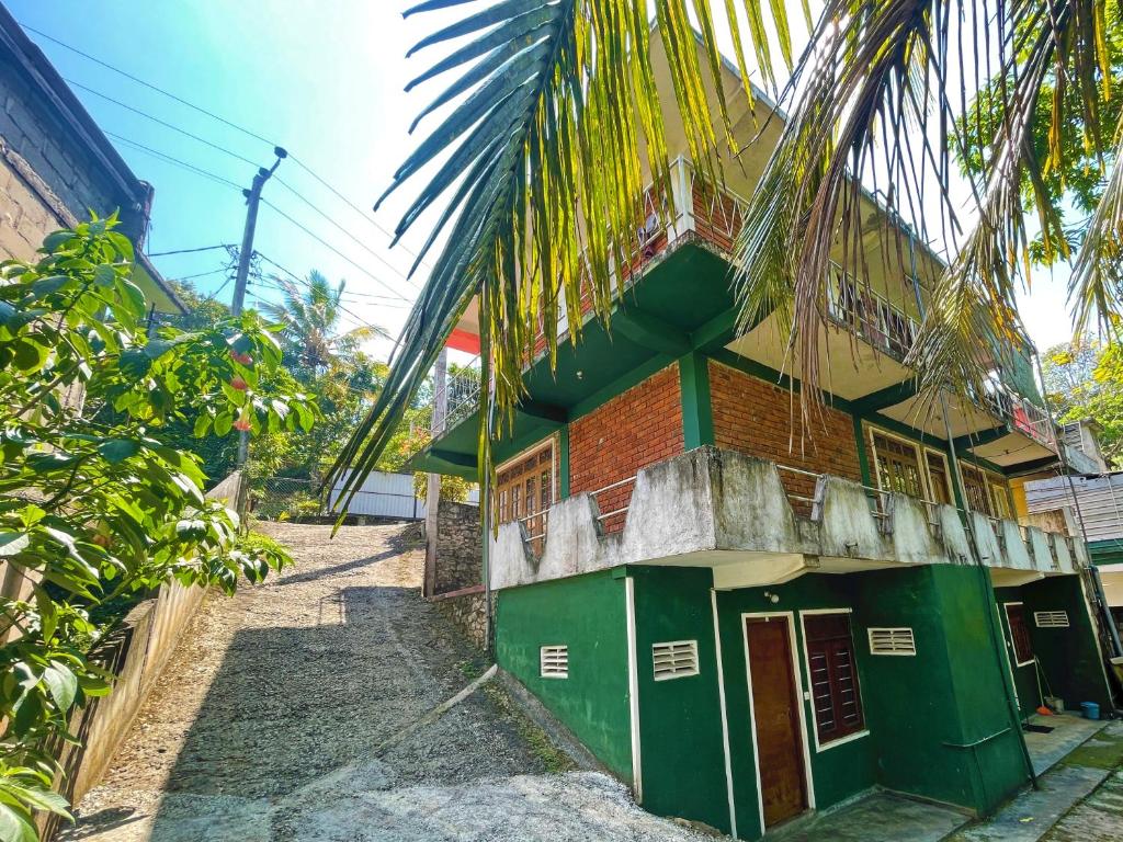 a building with green doors and a palm tree at Dealings Freedom Rest in Gampola