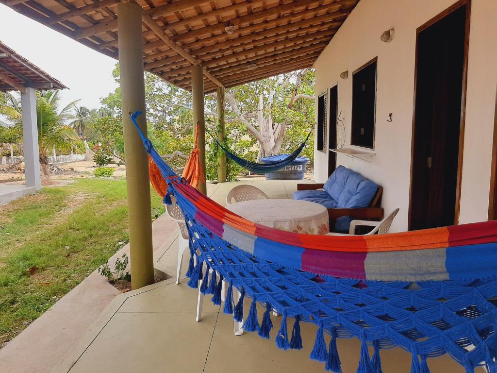 a hammock on the porch of a house at CHALE PERTO DA PRAIA COM DUAS SUITES E VARANDAO in Pacatuba