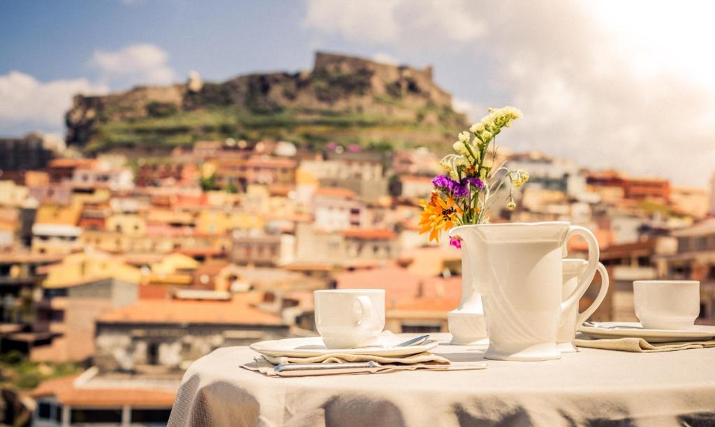 a table with two cups and a vase with flowers at Janus Hotel in Castelsardo