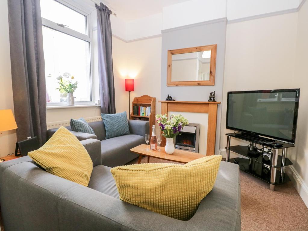 a living room with a gray couch and a tv at Combe Cottage in Millom