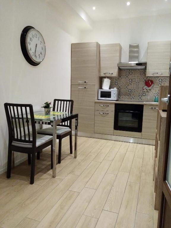 una cucina con tavolo, sedie e orologio sul muro di Appartamento Turistico "ortensia" ad Ancona