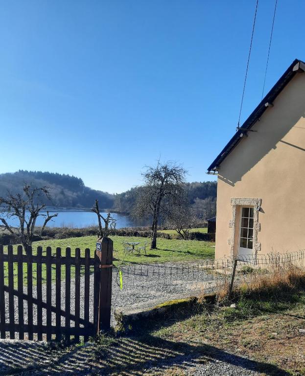 une clôture à côté d'une maison avec un lac en arrière-plan dans l'établissement Gite de l'Etang, Rangère Rural, à Villapourçon