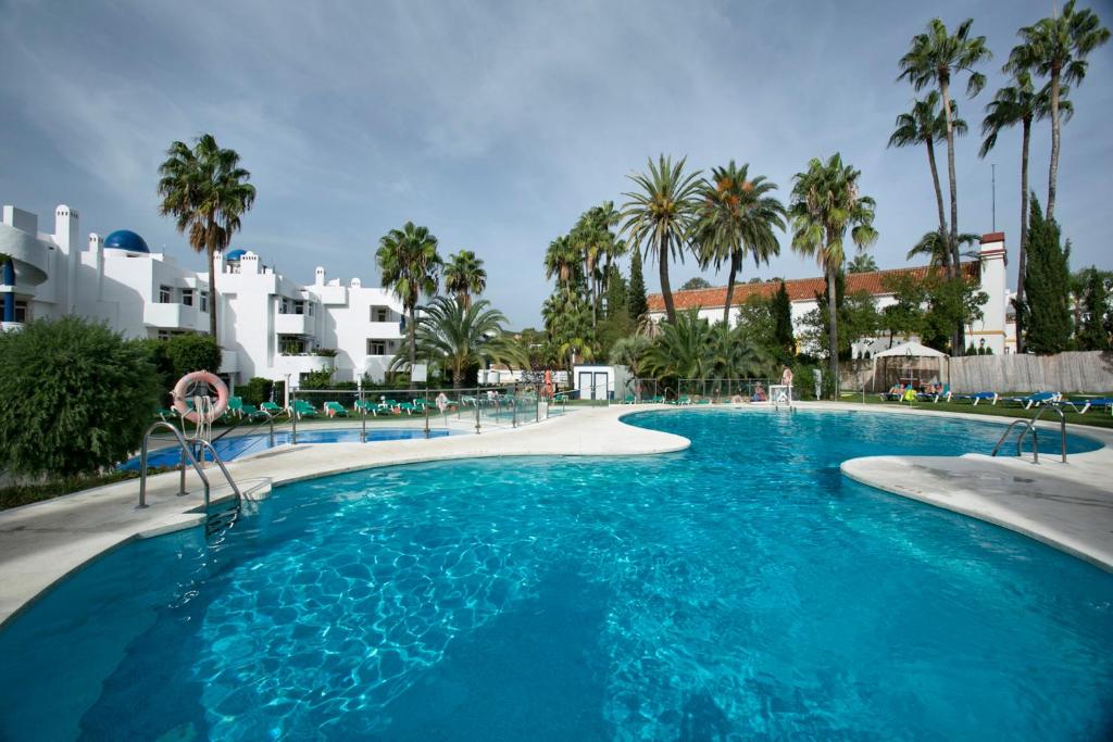 una gran piscina con palmeras y edificios en Aparthotel Ona Campanario en La Cala de Mijas