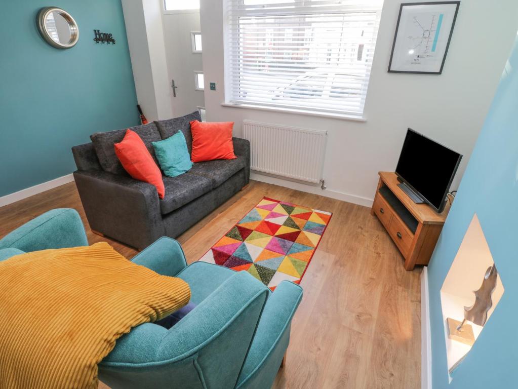 Una sala de estar con un sofá y un televisor. en Sea Glass, en Filey