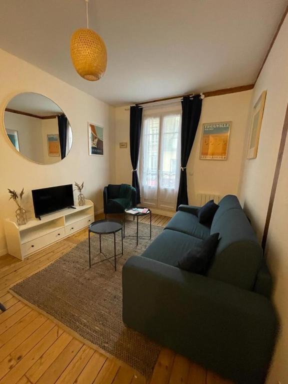un salon avec un canapé bleu et un miroir dans l'établissement Le « Blanc Bleu »-charmant 2 pièces /3 min Gare, à Trouville-sur-Mer