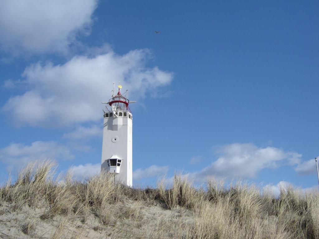 a white lighthouse sitting on top of a hill at Appartement "Zicht op de Vuurtoren" in Noordwijk aan Zee