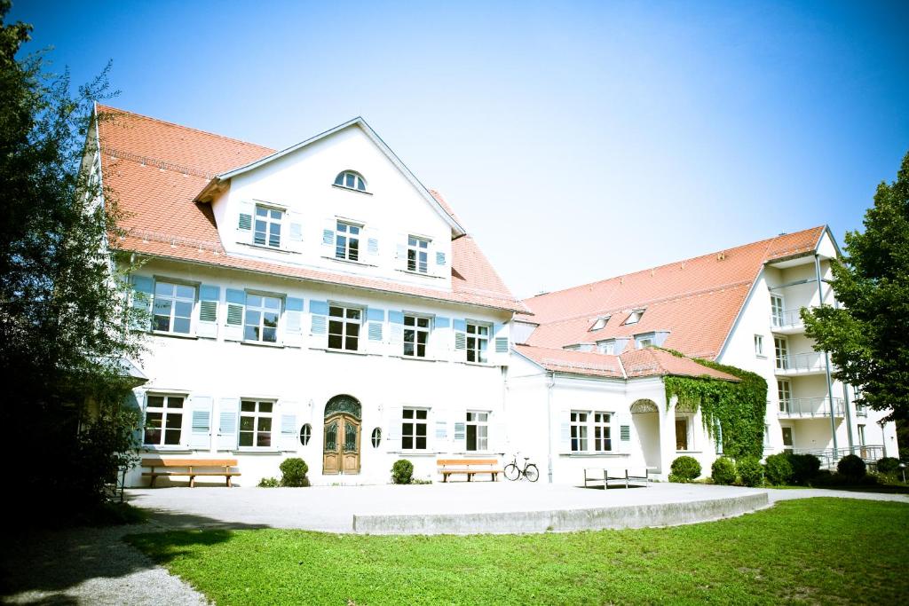 ein großes weißes Gebäude mit Bänken im Hof in der Unterkunft HI Youth Hostel Lindau in Lindau