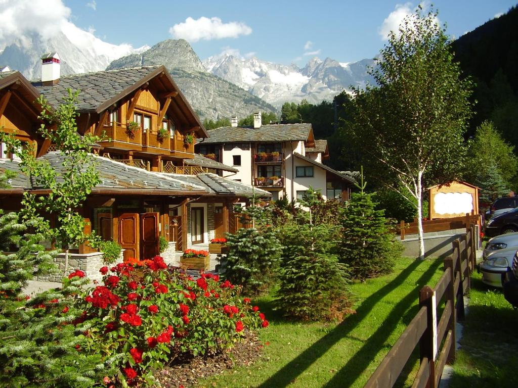 a wooden house with flowers and mountains in the background at Residence Cour Maison in Pré-Saint-Didier