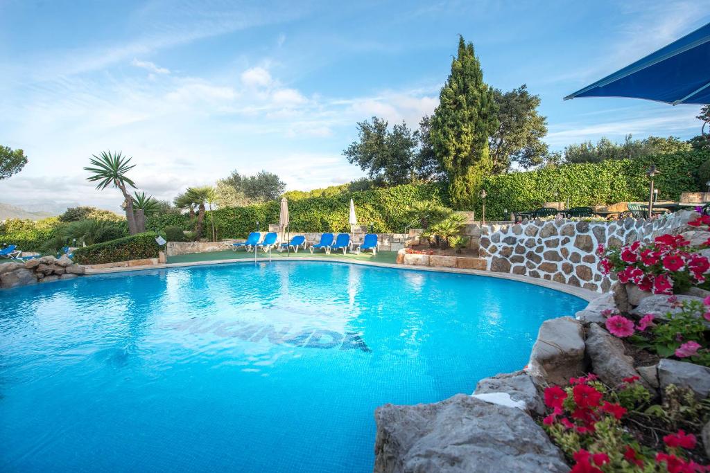 una gran piscina con sillas azules en un patio en Aparthotel Ona Aucanada, en Puerto de Alcudia