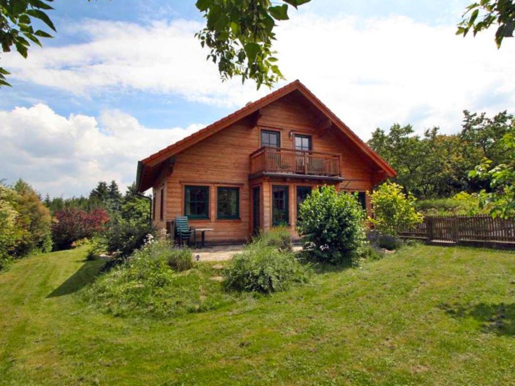 a log cabin with a deck on a grass field at Holiday Home Haus Fries by Interhome in Unterbergern