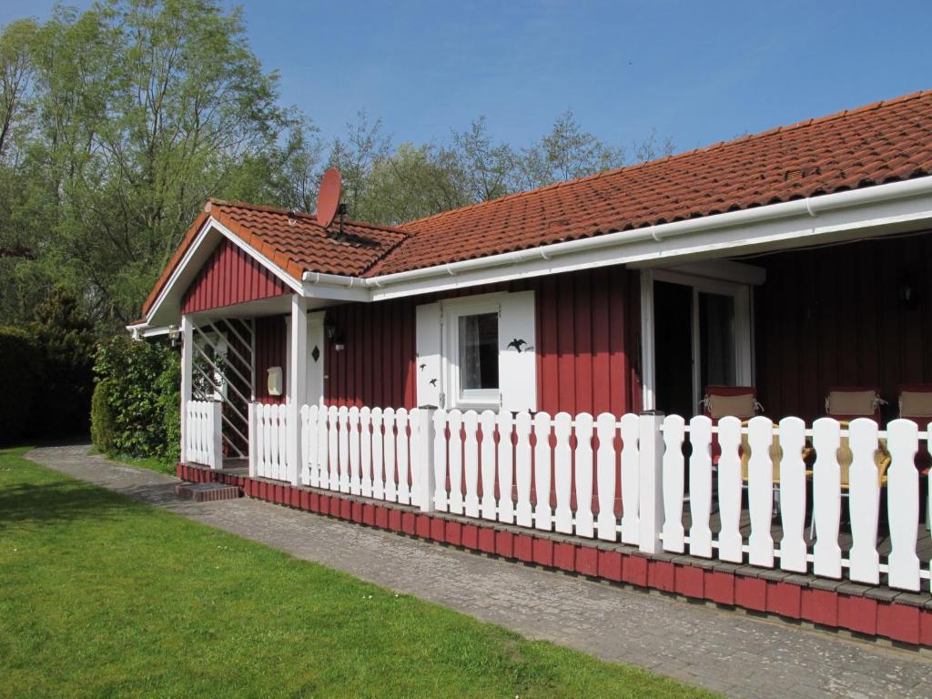 een rood-wit huis met een wit hek bij Chalet Martin by Interhome in Otterndorf