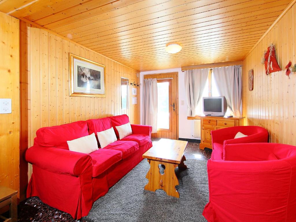 ein Wohnzimmer mit einem roten Sofa und 2 Stühlen in der Unterkunft Apartment Rousserolles 1 by Interhome in Verbier