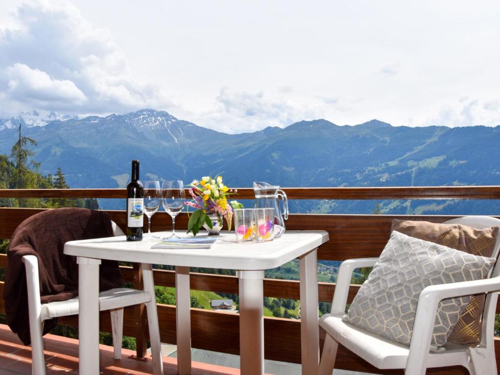 una mesa con copas de vino y flores en el balcón en Apartment Mondzeu A258 by Interhome, en Verbier