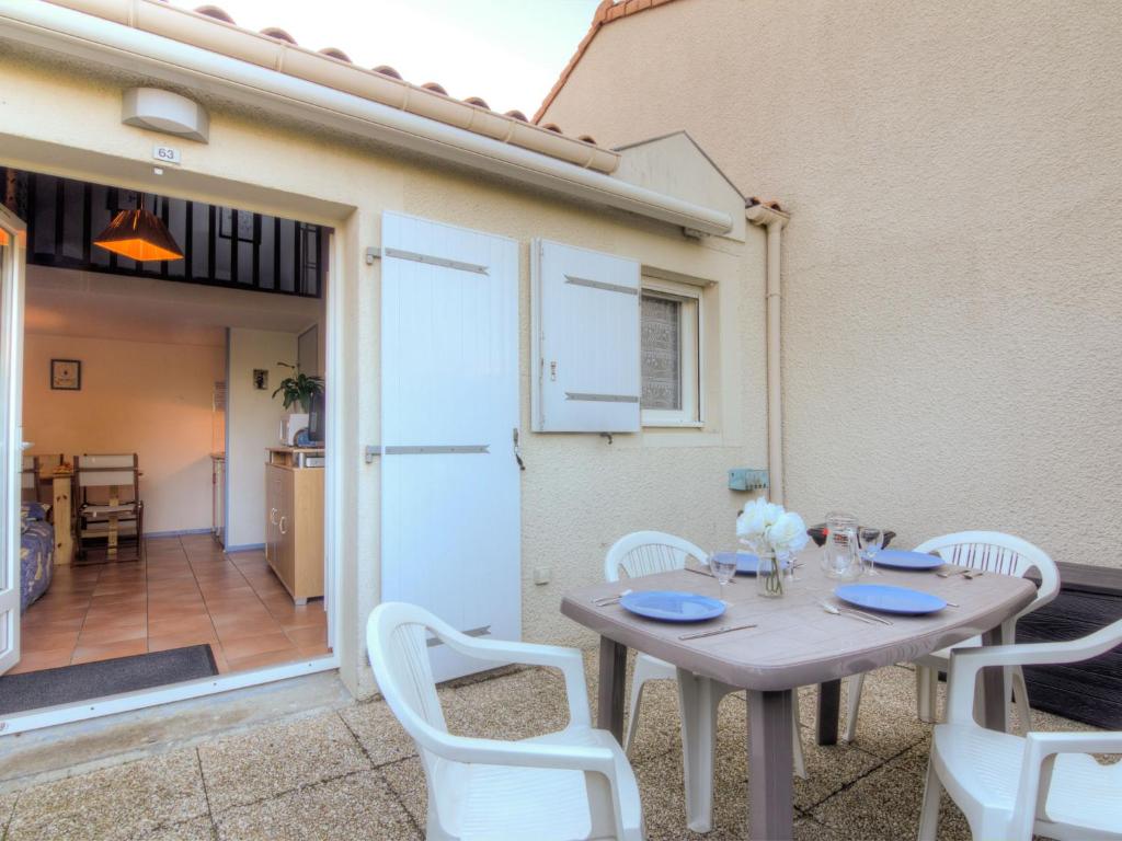 a table with white chairs and a door to a kitchen at Holiday Home Les Jardins de l'Océan-2 by Interhome in Pontaillac
