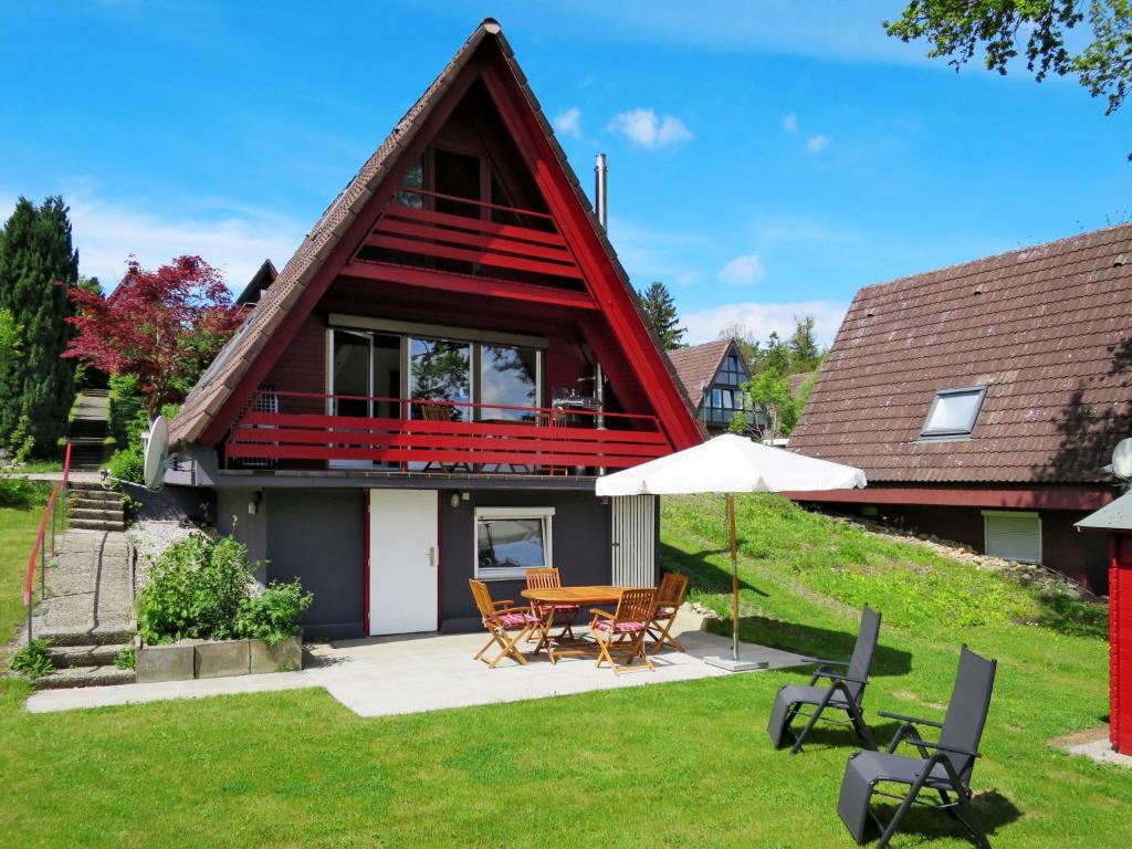 a house with a red roof with a table and chairs at Holiday Home Svea by Interhome in Wilhelmsdorf