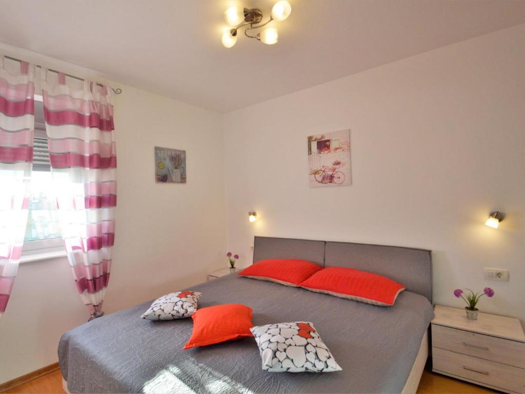 sypialnia z łóżkiem z czerwonymi poduszkami w obiekcie Apartment Pinezic by Interhome w Rovinj