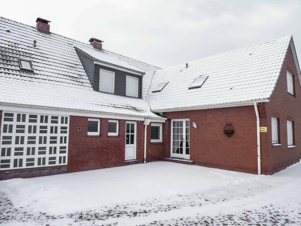 ein rotes Backsteinhaus mit Schnee auf dem Boden in der Unterkunft Apartment Am Nordkap-2 by Interhome in Norddeich