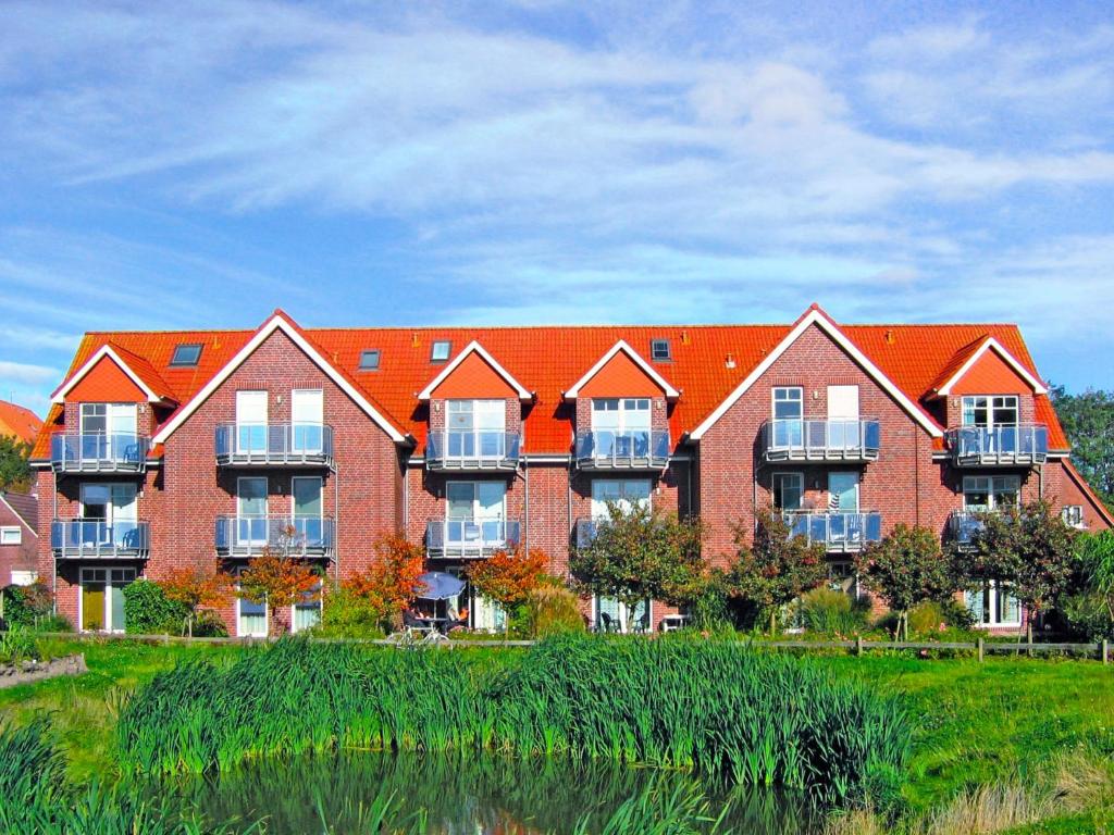 a large red brick building with balconies next to a body of water at Apartment Frisiastrasse-1 by Interhome in Norddeich