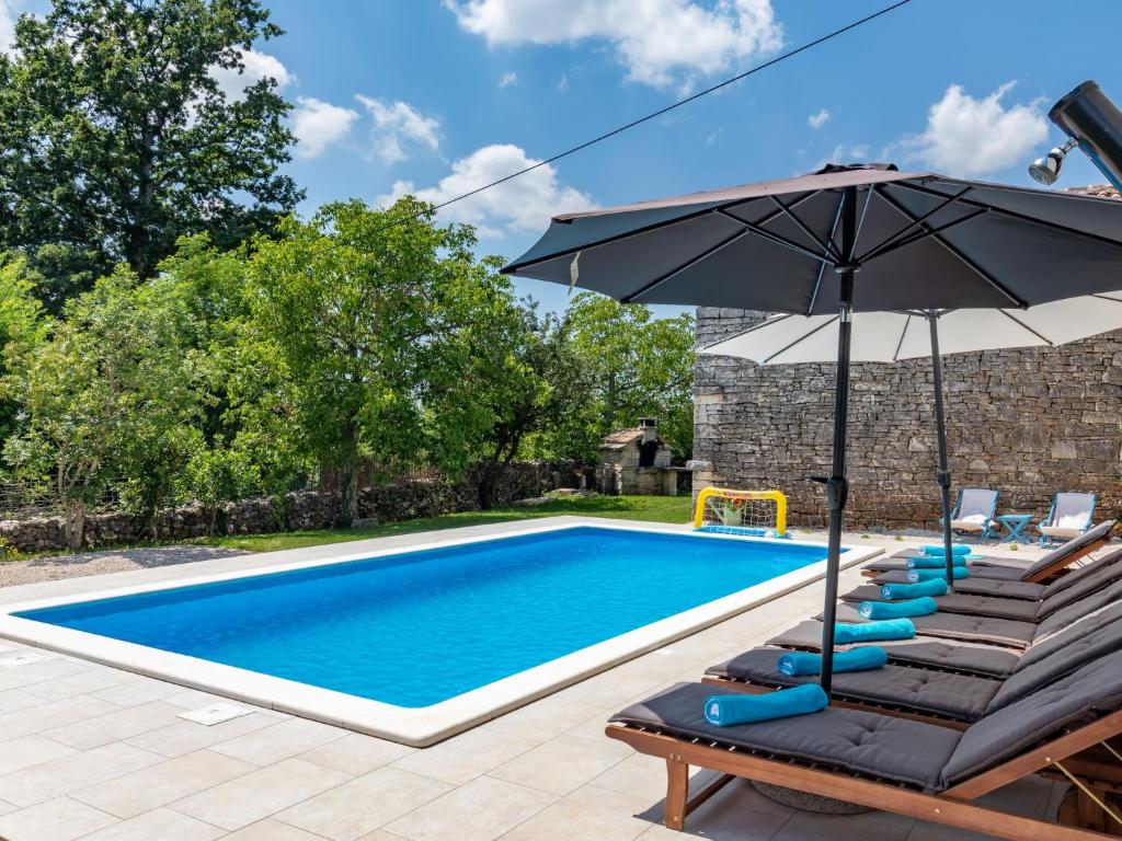 una piscina con tumbonas y sombrilla en Holiday Home Marija - ROJ422 by Interhome en Žminj