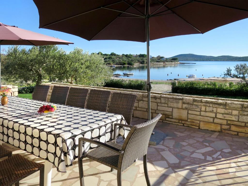 a table and chairs with an umbrella and a view of a lake at Holiday Home Julija - VOD300 by Interhome in Pirovac