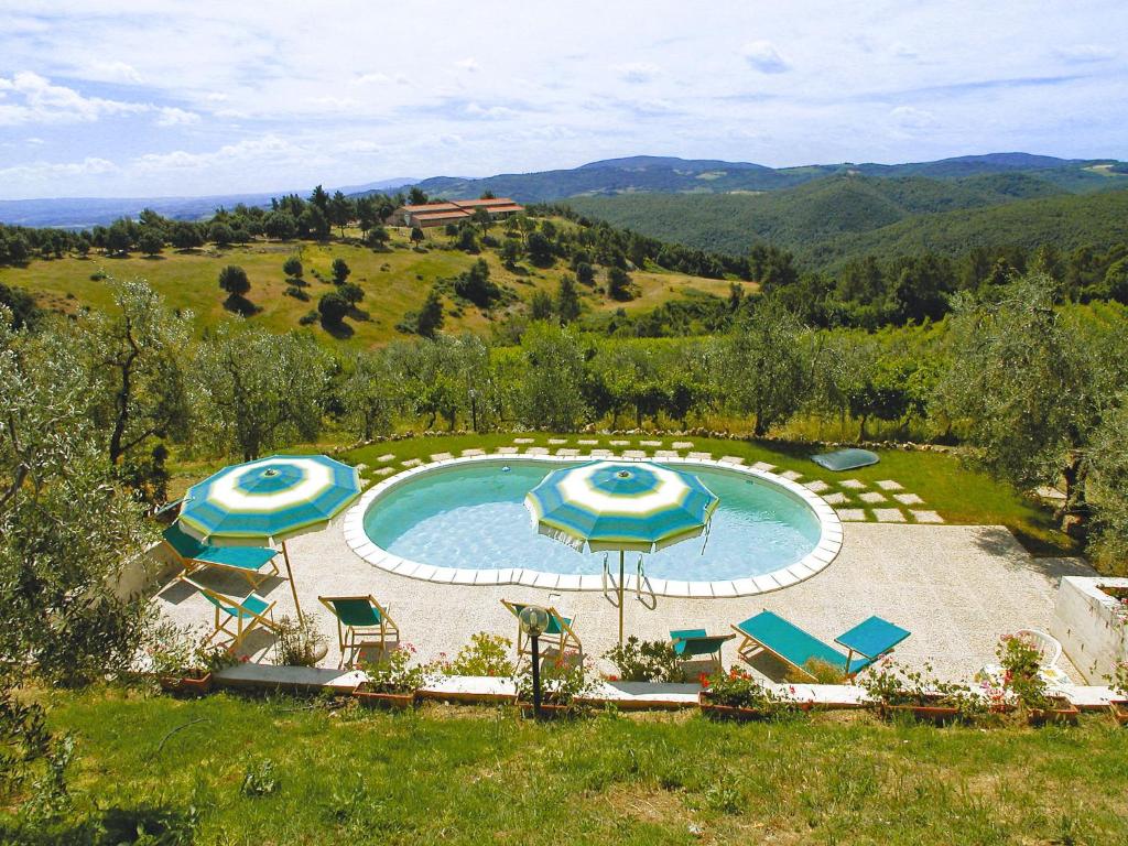 a swimming pool with umbrellas and chairs in a field at Apartment I Ceneruzzi-2 by Interhome in Gambassi Terme