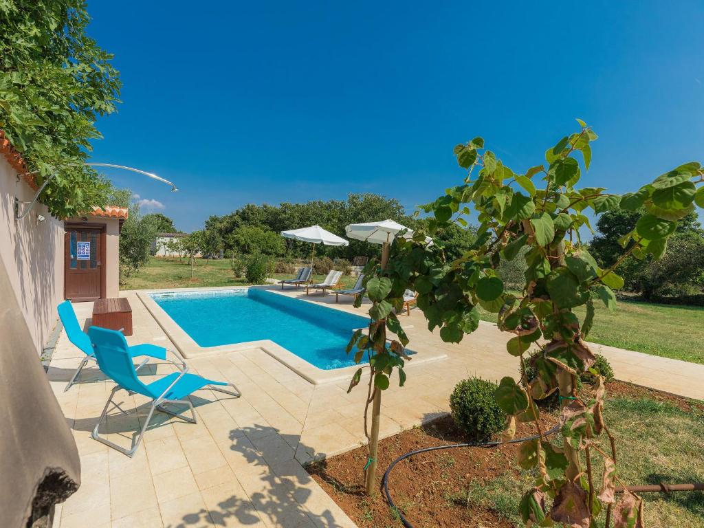 a swimming pool with two chairs and a tree at Holiday Home Lancin - RCA452 by Interhome in Marčana