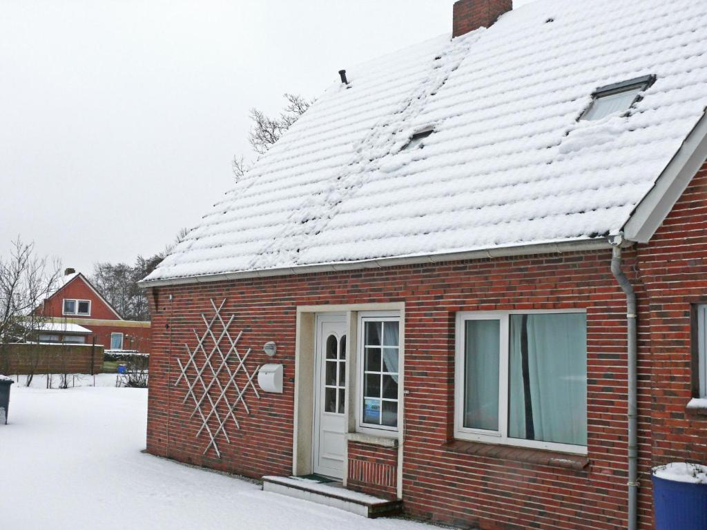 ein rotes Backsteinhaus mit Schnee auf dem Dach in der Unterkunft Apartment Tunnelstrasse-1 by Interhome in Norddeich