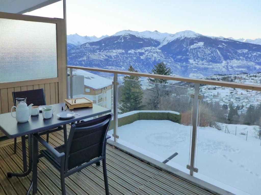 a balcony with a table and a view of a snow covered mountain at Apartment Clair-Azur B 65 by Interhome in Randogne