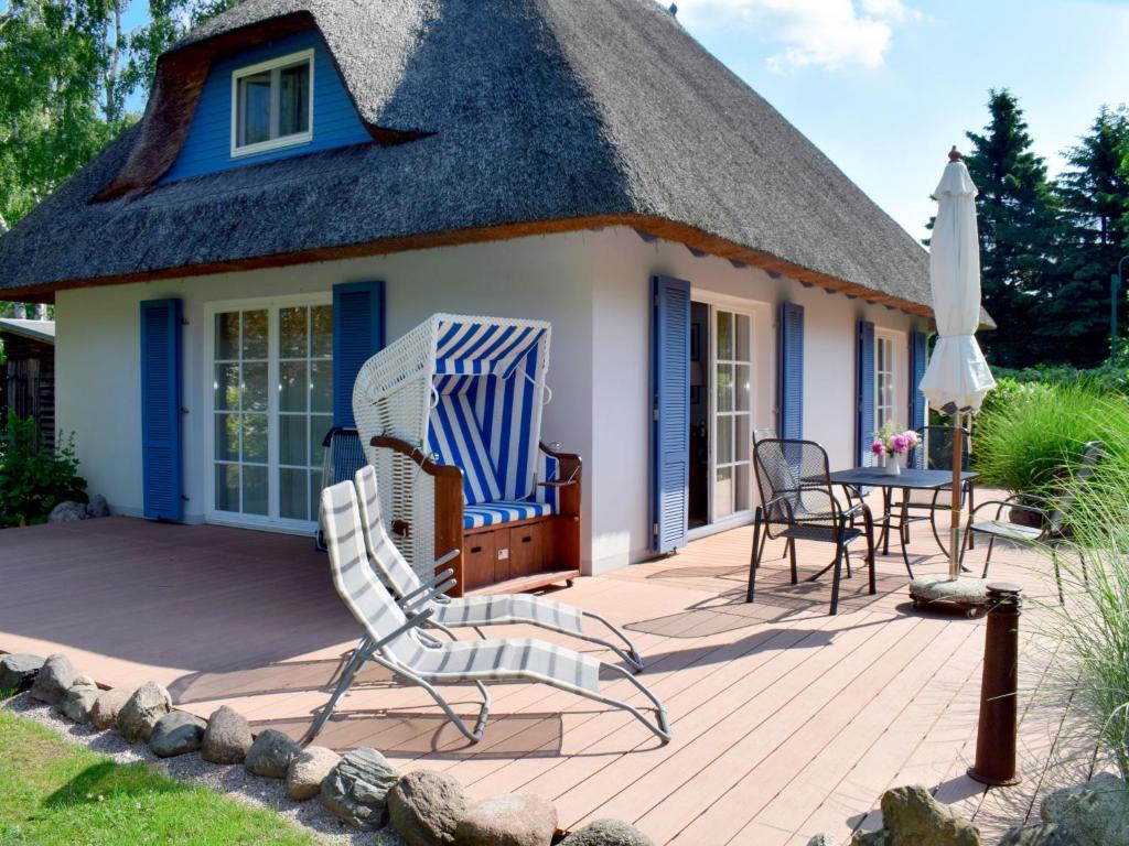 a thatched cottage with a patio and a table and chairs at Holiday Home Katja by Interhome in Ostseebad Karlshagen