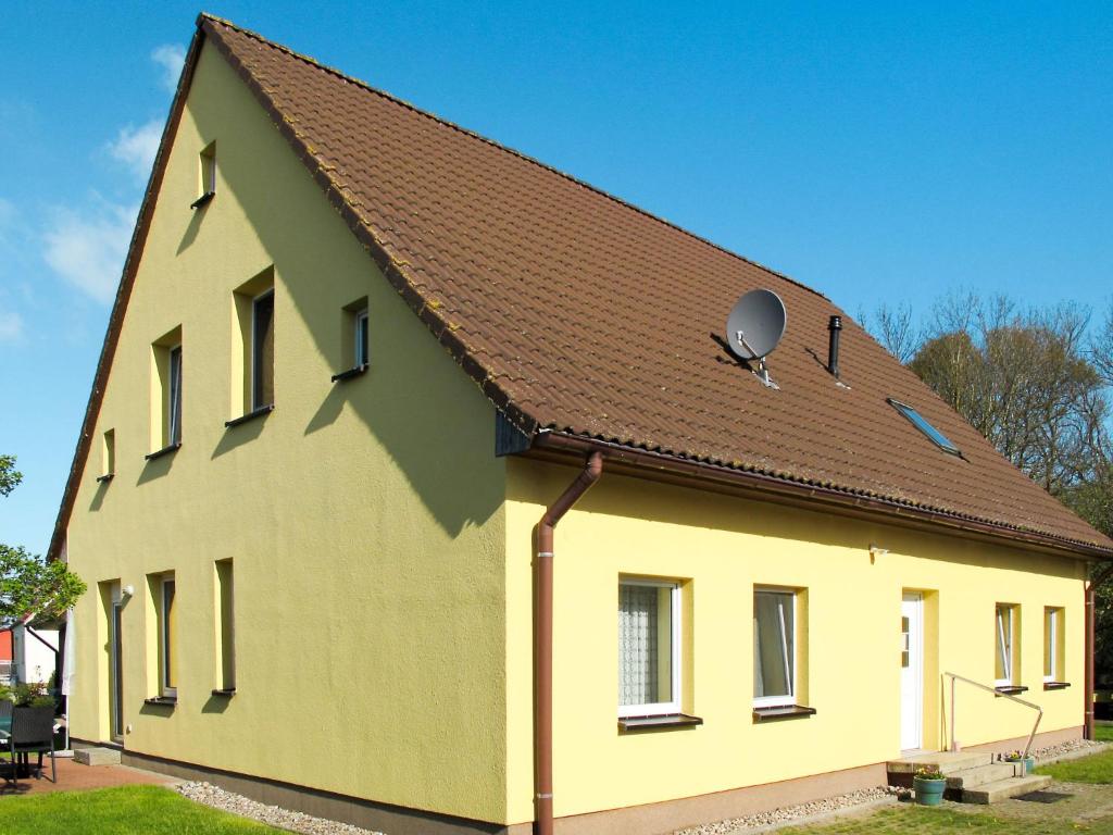 a large yellow building with a brown roof at Apartment Am Strom-4 by Interhome in Ummanz