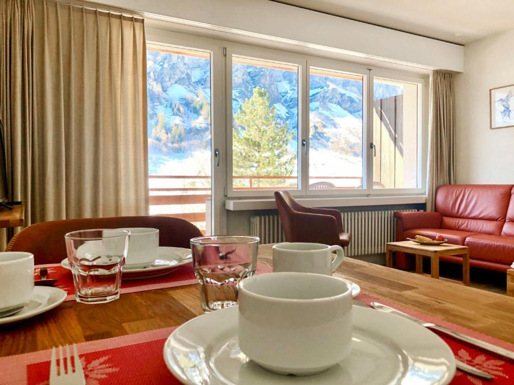 a dining room with a table with plates and cups at Apartment Ringstrasse - Utoring-3 by Interhome in Leukerbad