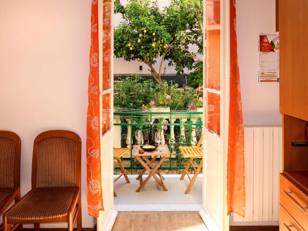 Une porte ouverte s'ouvre sur un balcon avec une table et des chaises. dans l'établissement Apartment Agnese by Interhome, à Sanremo