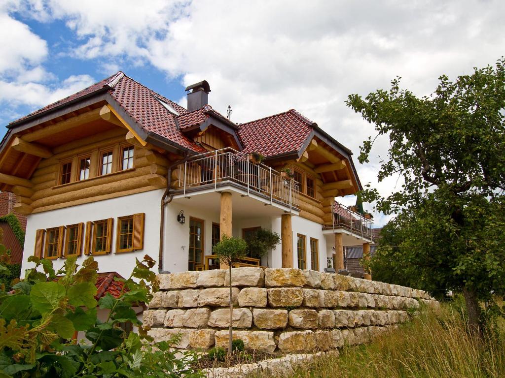 ein großes Holzhaus mit einer Steinmauer in der Unterkunft Apartment Fichte by Interhome in Schönbronn