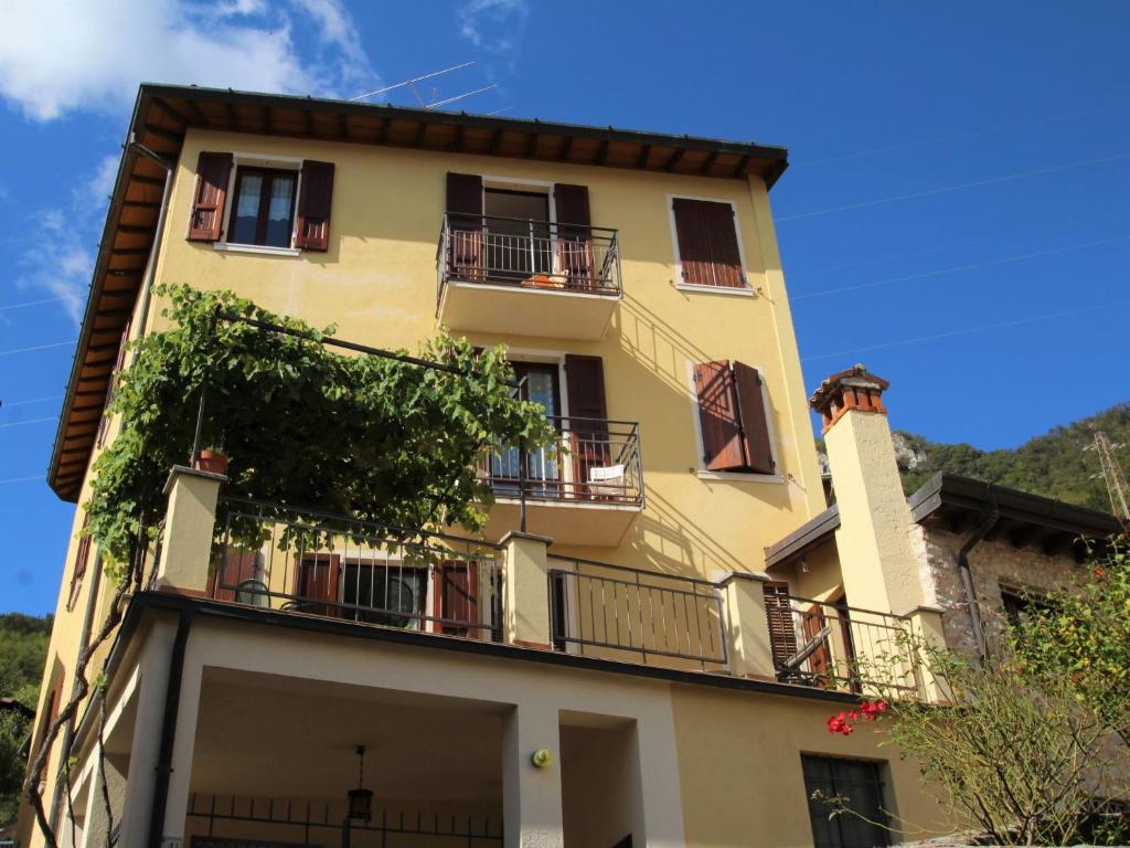 un edificio giallo alto con balconi e alberi di Apartment Formaga-1 by Interhome a Gargnano