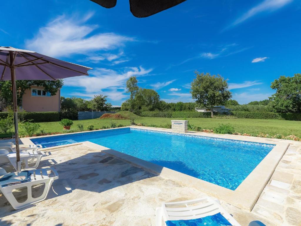 uma piscina com cadeiras e um guarda-sol em Holiday Home Ana Lucija - RCA508 by Interhome em Pula