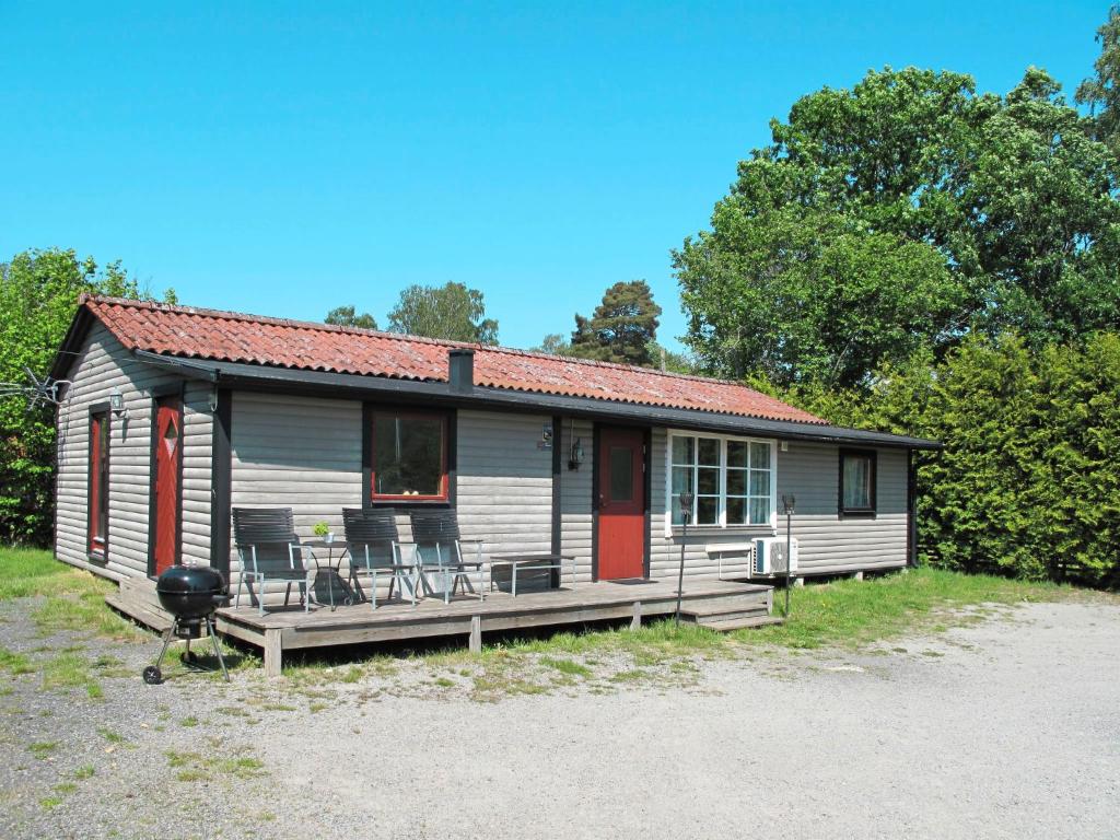 een klein huis met een veranda en een grill bij Holiday Home Hoka Stugan - B in Asarum