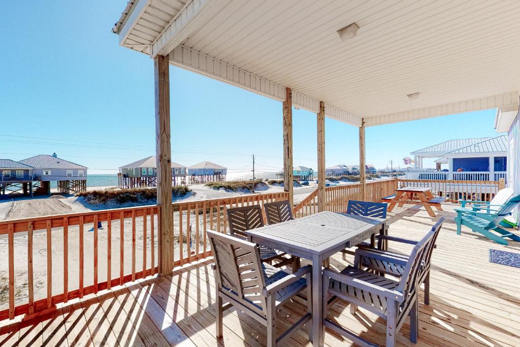 a table and chairs on a deck with the beach at Sandtastic in Dauphin Island