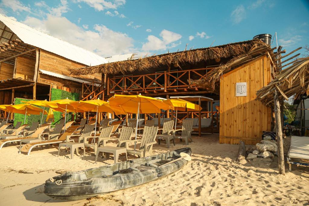 eine Gruppe von Stühlen und Sonnenschirmen am Strand in der Unterkunft Soy Local Barú in Barú