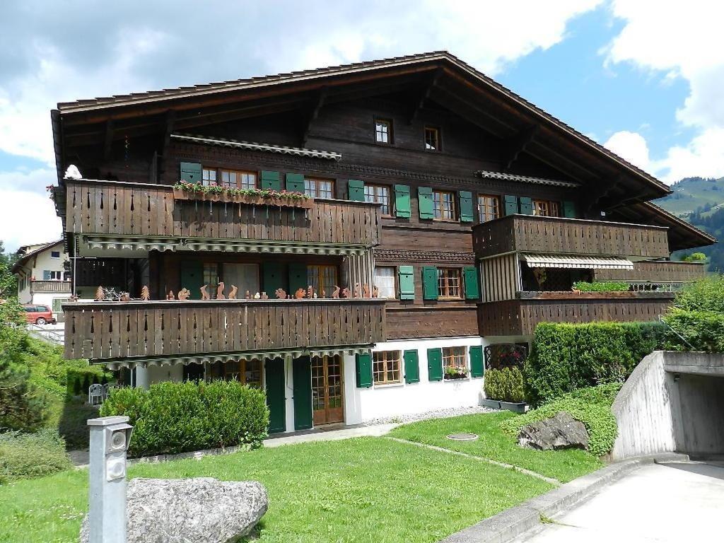 ein großes Holzgebäude mit Menschen auf dem Balkon in der Unterkunft Apartment Gletscherhorn II - Tapia by Interhome in Zweisimmen